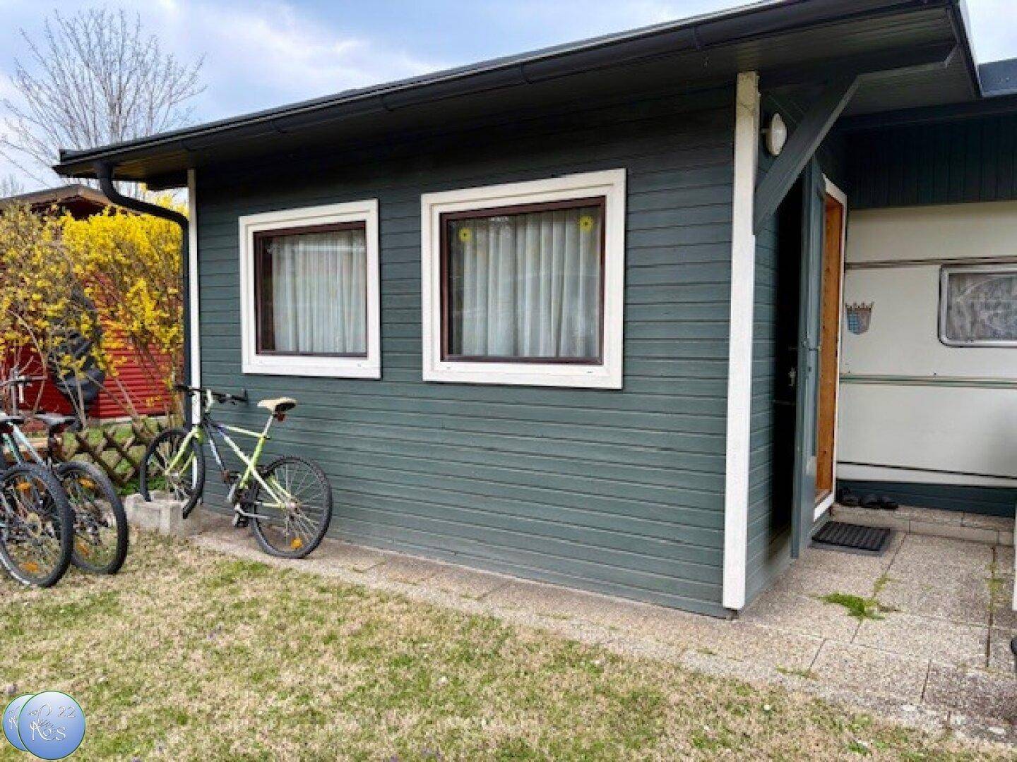 Seitenansicht des Ferienhauses mit Holzverkleidung, Fenstern und abgestellten Fahrrädern.