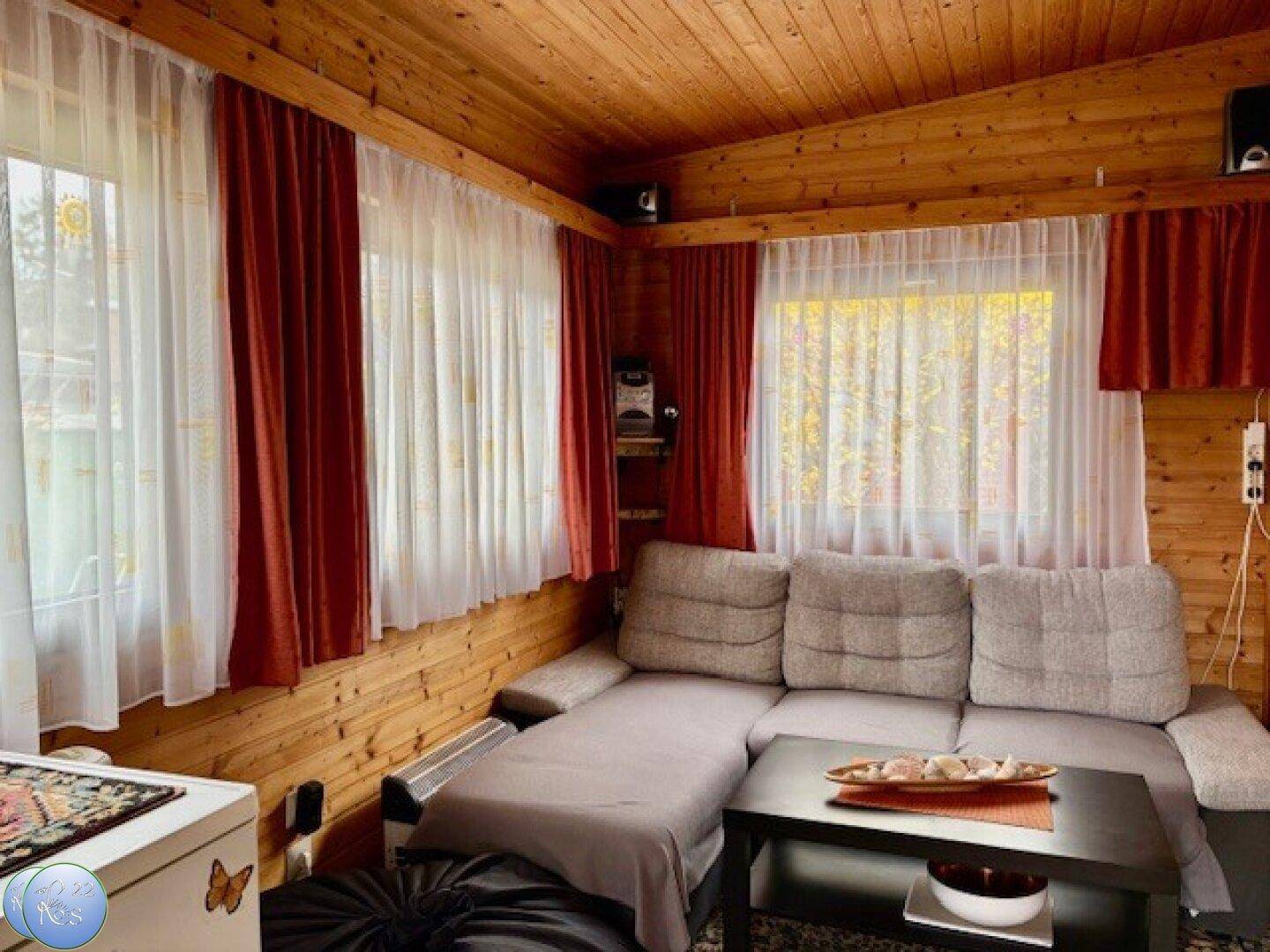 Gemütliches Wohnzimmer mit Holzvertäfelung, bequemer Couch und viel natürlichem Licht.