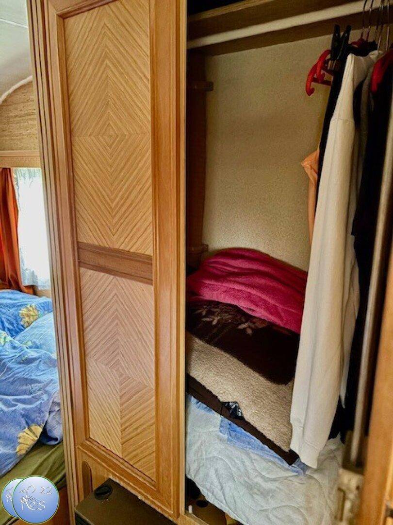 Integrierter Kleiderschrank mit Holztüren und Stauraum für Kleidung im Schlafbereich.