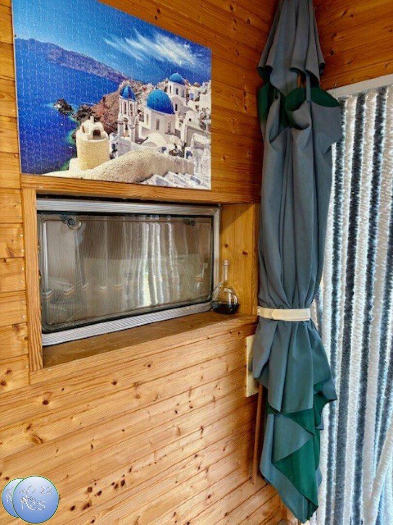 Holzverkleidete Wand mit einem kleinen Fenster und einem dekorativen Bild.