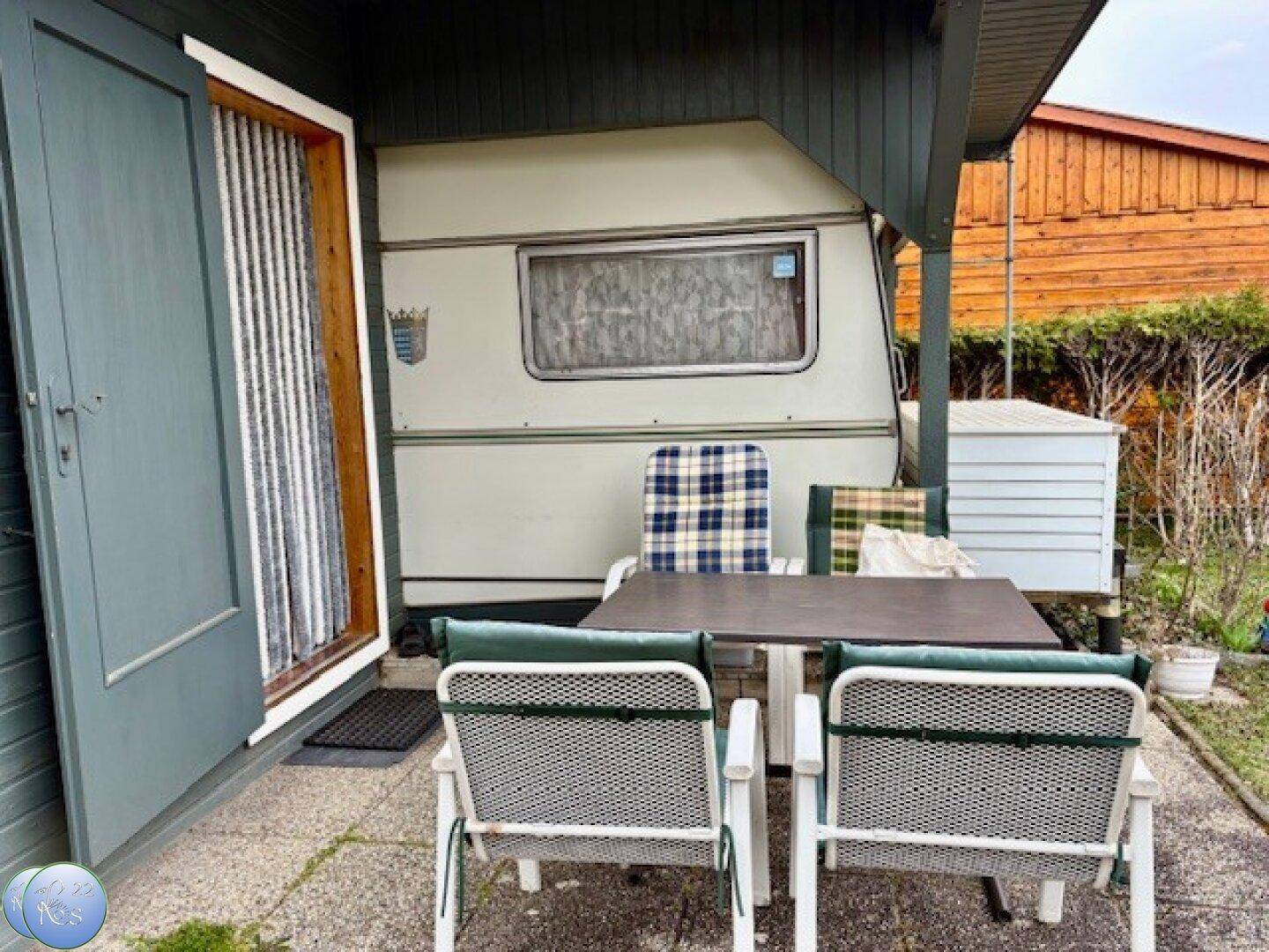 Möblierte Terrasse direkt am Wohnwagen mit Blick auf den Gartenbereich.