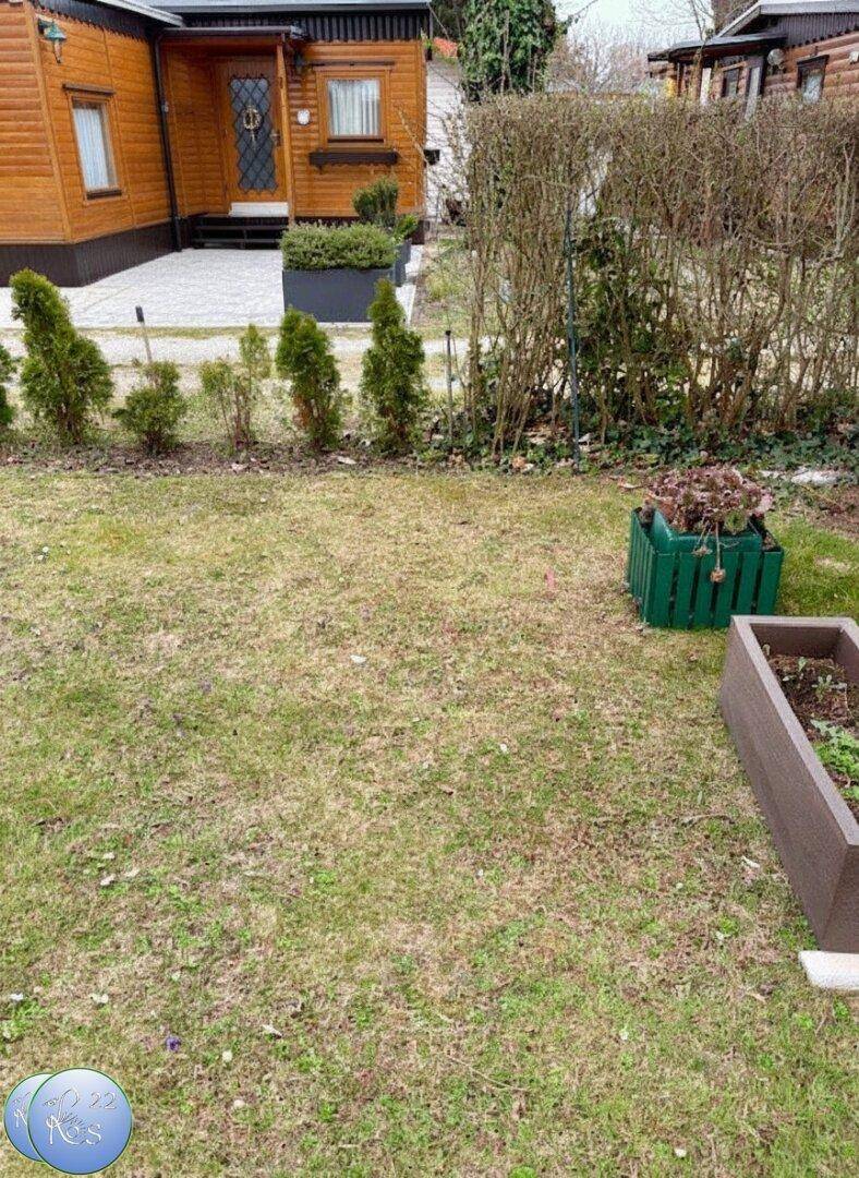 Weitläufiger Gartenbereich mit Rasenfläche, Hecke und angrenzendem Nachbargrundstück.