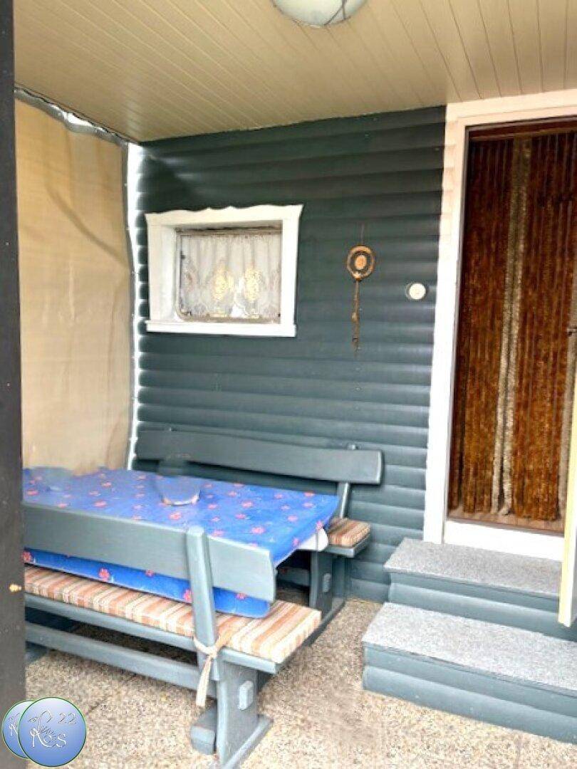 Überdachte Terrasse mit Holzbänken und Tisch, ideal für Mahlzeiten im Freien.