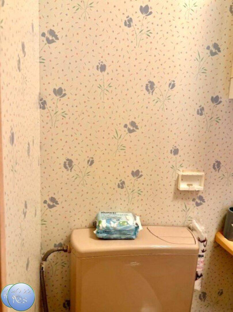 Separate Toilette mit floraler Tapete und einem traditionellen WC-Becken.