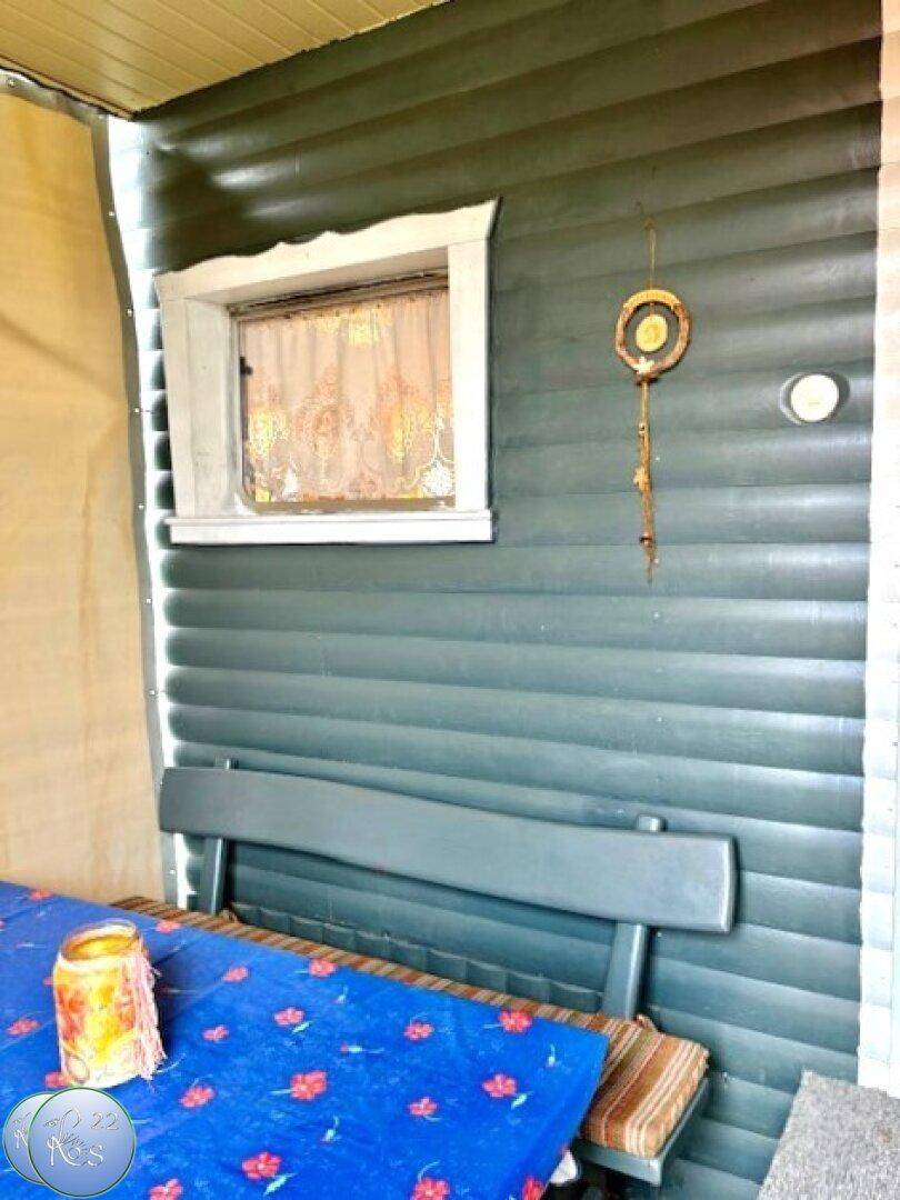 Detailansicht der überdachten Terrasse mit Holzbänken und dekorativen Elementen.