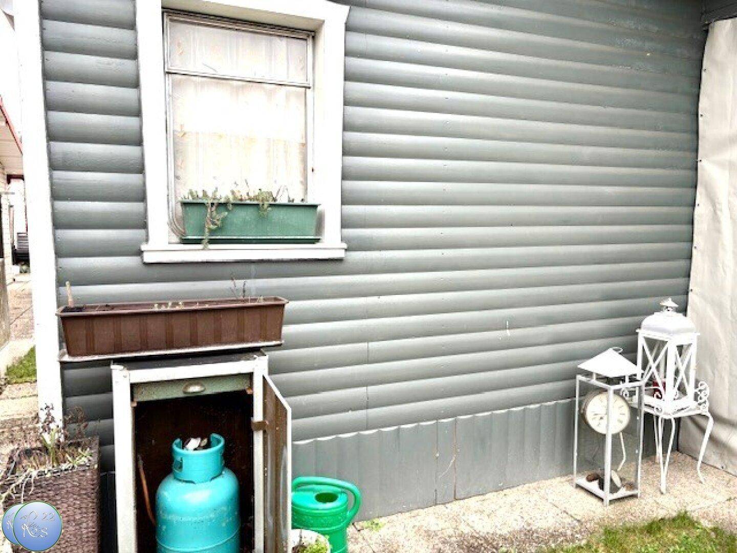 Außenwand des Gebäudes mit Fenster, Gasflasche und dekorativen Laternen.
