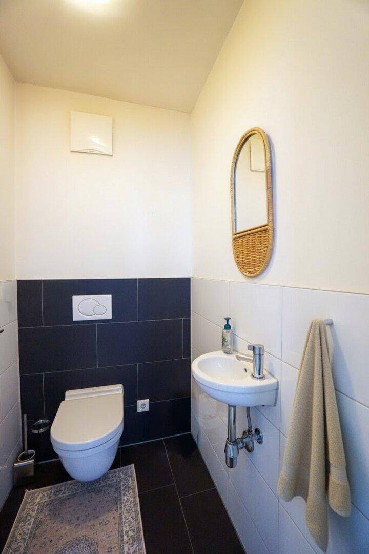 Modernes Gäste-WC mit dunklen Fliesen und kleinem Waschbecken.