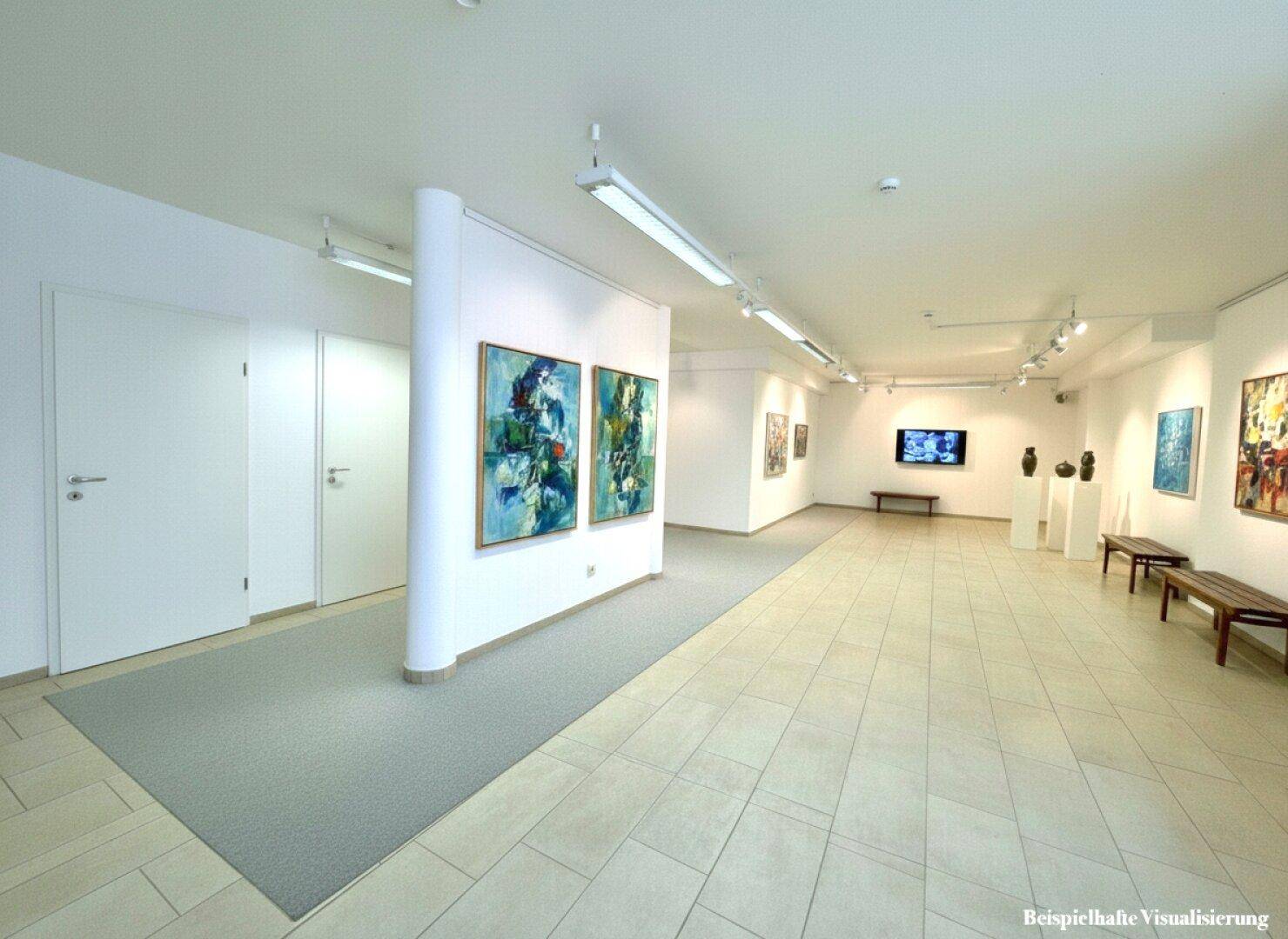 Weiter Ausstellungsraum mit Kunstwerken, Sitzbänken und einer Trennwand, die den Raum strukturiert.