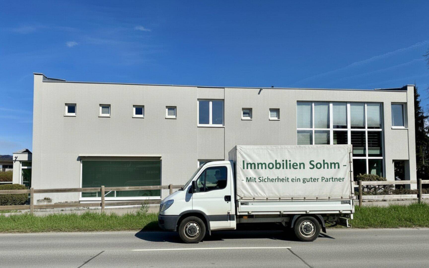 Modernes Gebäude mit heller Fassade und großen Fensterfronten, das eine zeitgemäße Architektur aufweist und an einer Straße liegt.