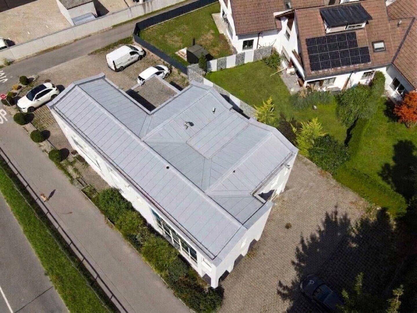 Detaillierte Luftaufnahme des Gebäudedachs mit seiner komplexen Struktur und dem angrenzenden Parkplatz.