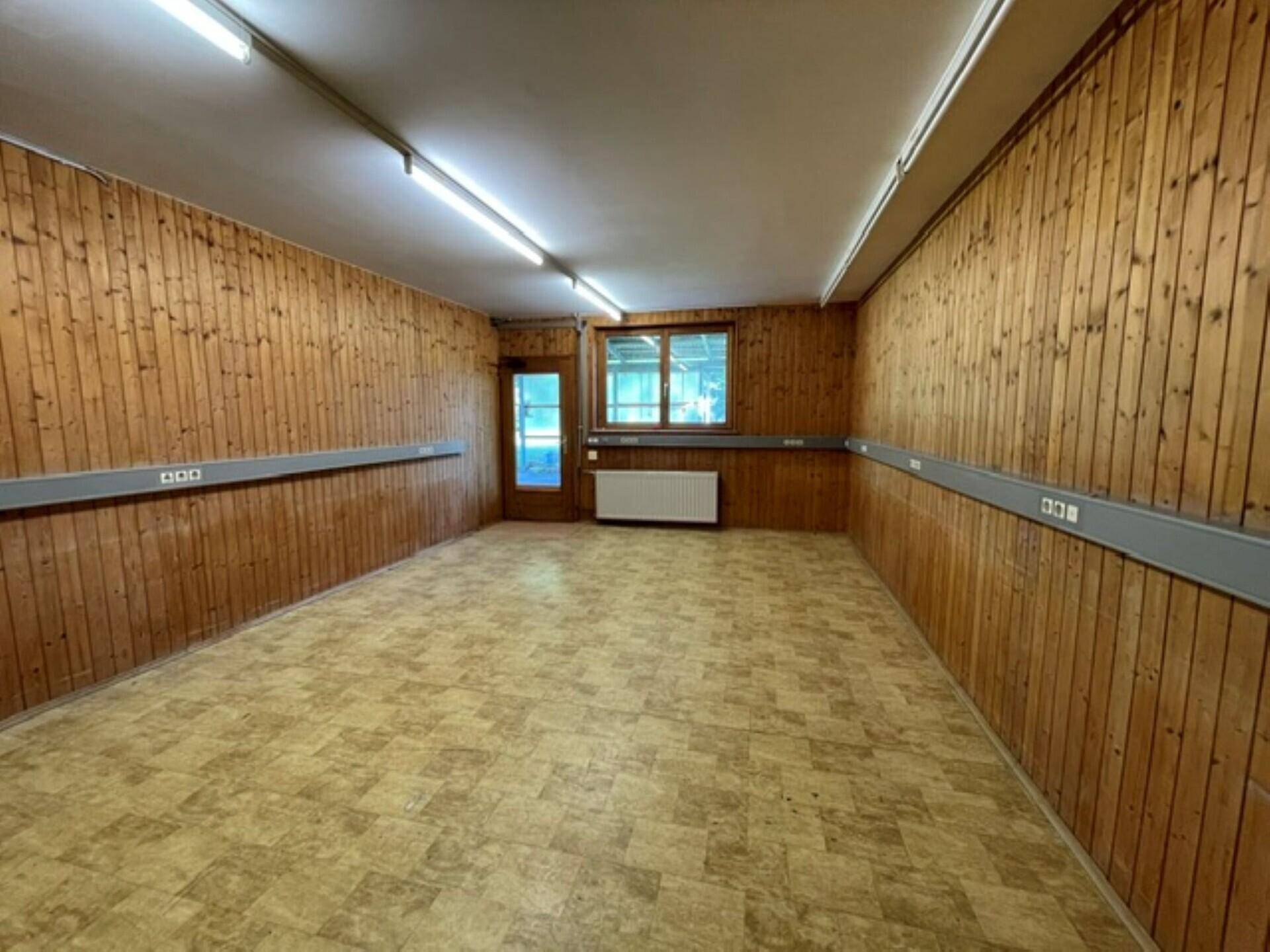 Innenraum mit Holzvertäfelung, einer Eingangstür und einem Fenster, das Tageslicht hereinlässt.