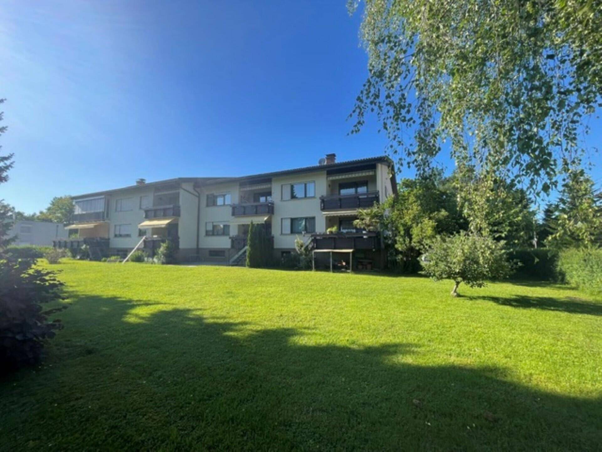 Mehrfamilienhaus mit großem Gemeinschaftsgarten und Balkonen in sonniger Lage.