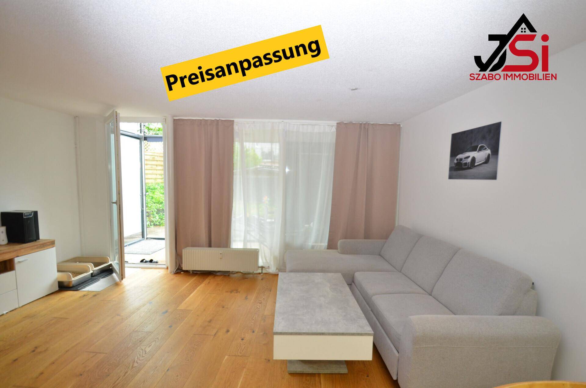 Helles Wohnzimmer mit Parkettboden, beigem Sofa und Zugang zum Gartenbereich.