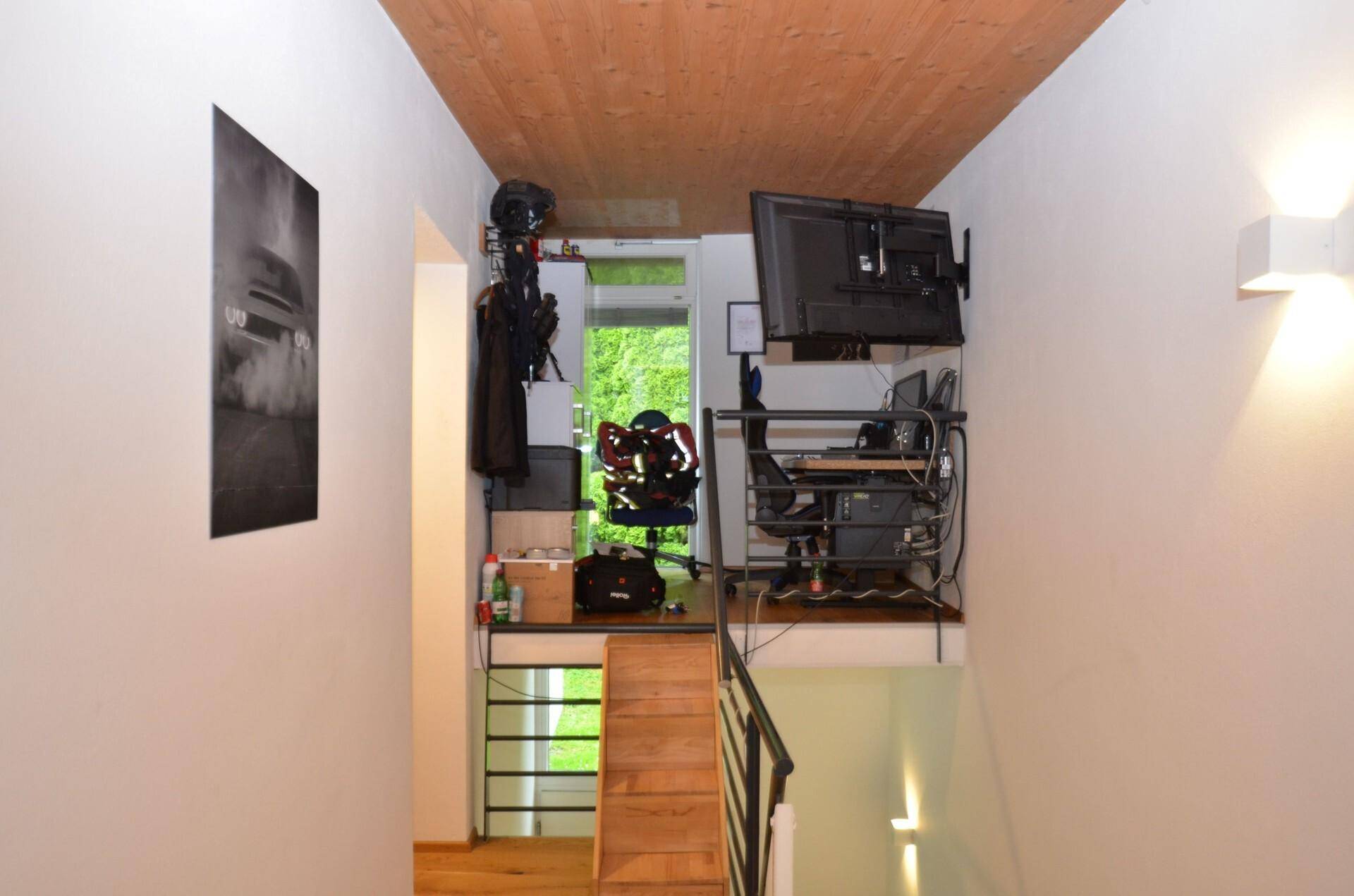 Kreativer Arbeitsbereich auf einer Galerie mit Holzdecke und Blick ins Grüne.