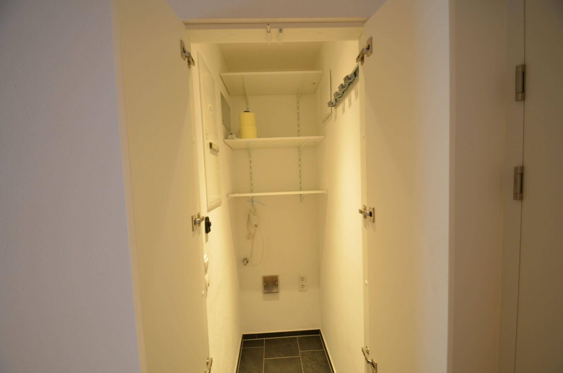 Praktischer Abstellraum mit Regalen und dunklem Fliesenboden, ideal für Haushaltsgeräte.