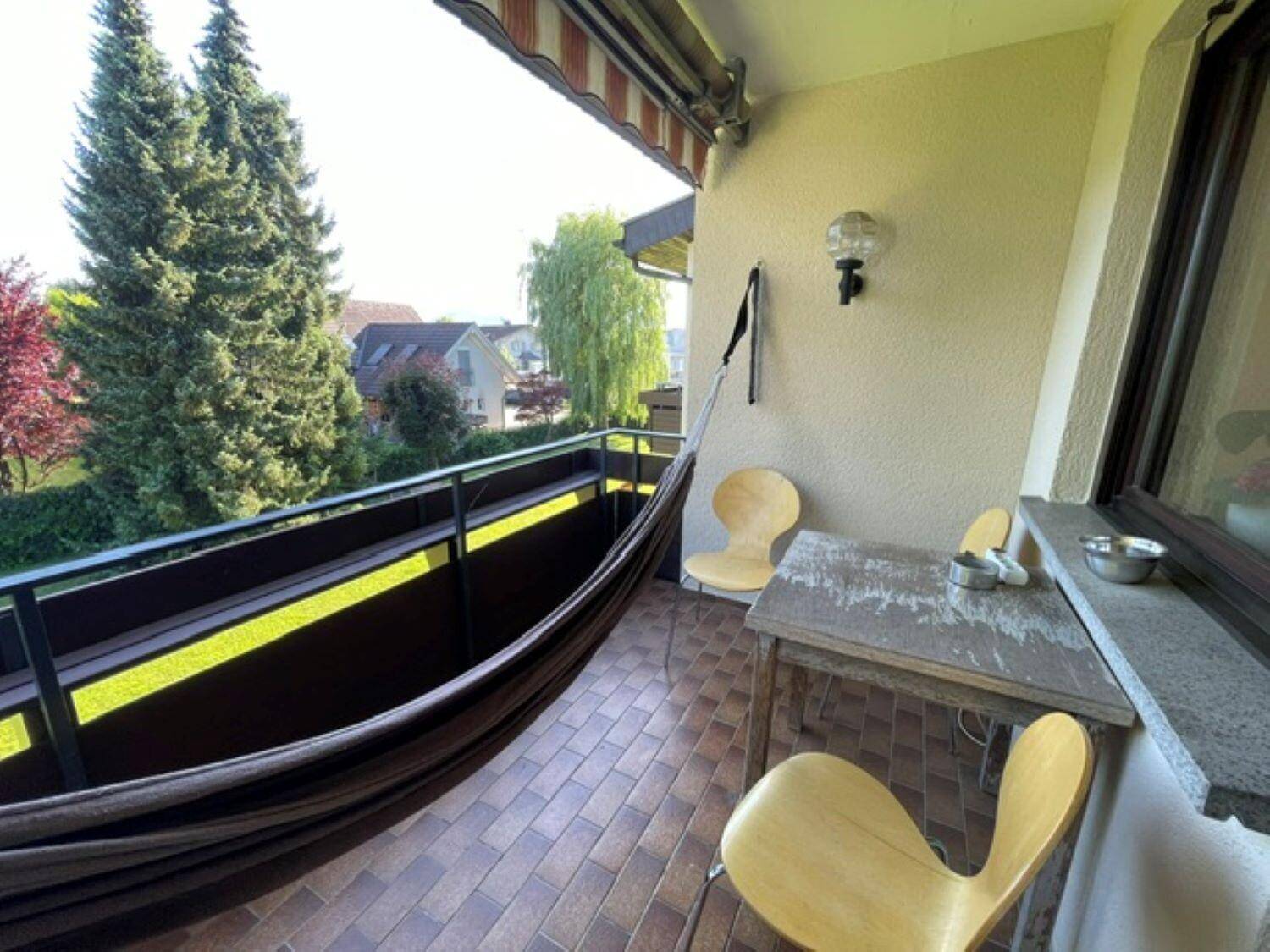 Gemütlicher Balkon mit Hängematte, Tisch und Stühlen, ideal zum Entspannen im Freien.
