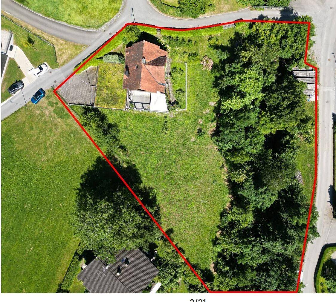 Luftaufnahme eines Grundstücks mit einem Haus und viel Grünfläche, rot umrandet.