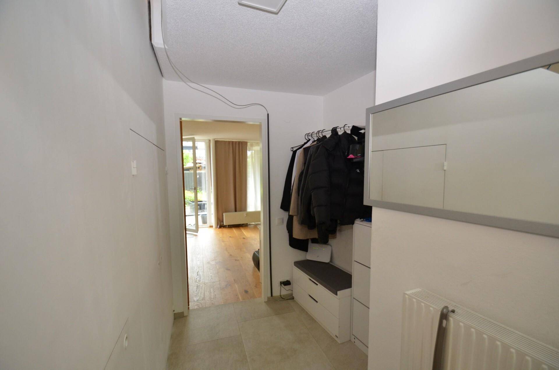 Eingangsbereich mit Fliesenboden, Garderobe und Spiegel, der zum Wohnbereich führt.