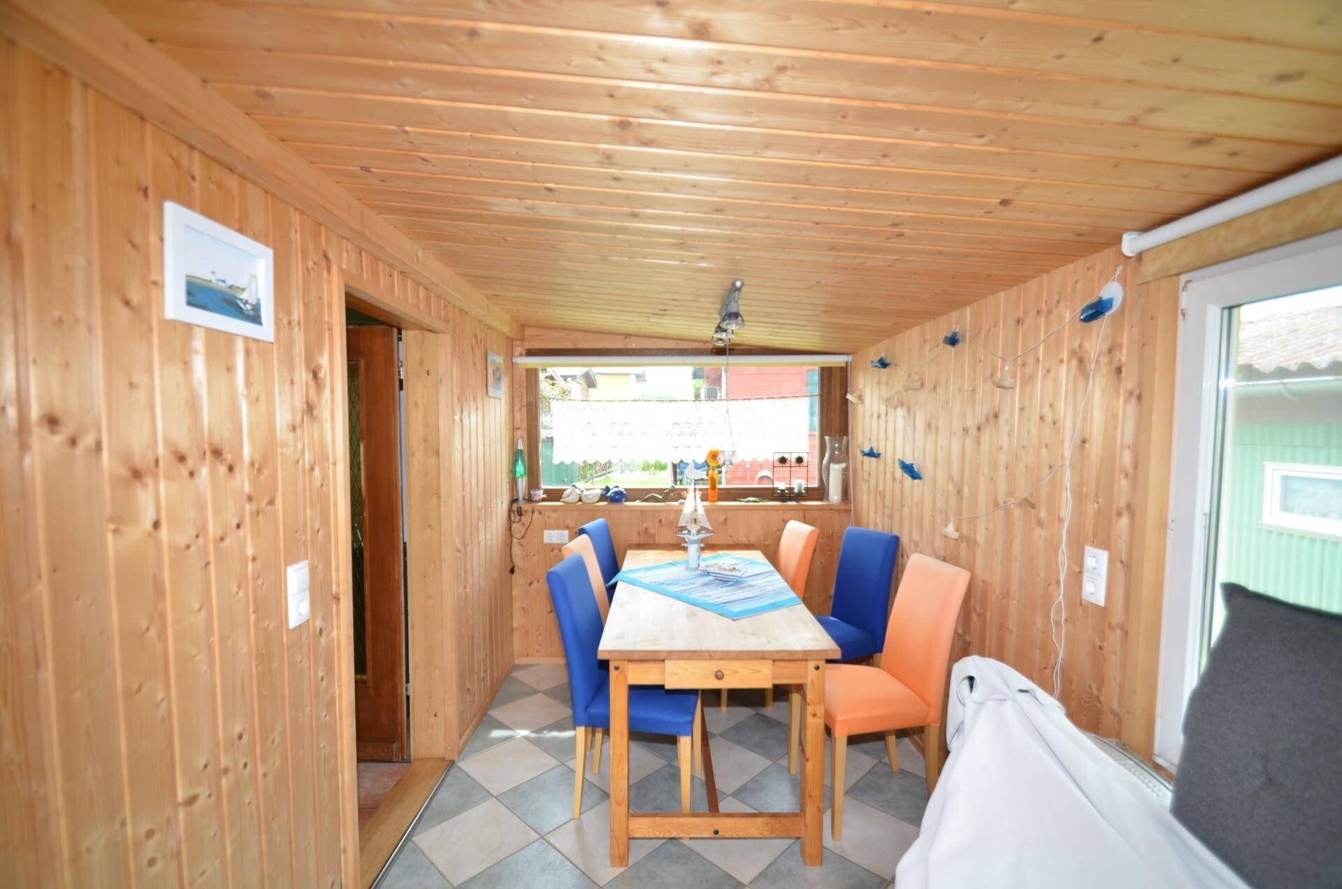 Essbereich mit Holzvertäfelung, Holztisch und bunten Stühlen, ideal für gesellige Runden.