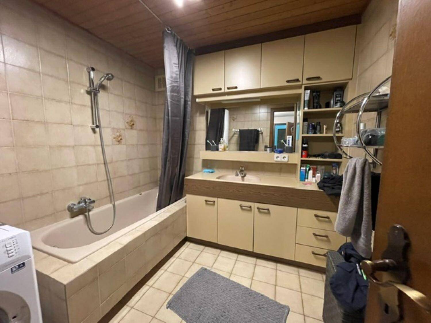 Badezimmer mit Badewanne, Dusche, Einzelwaschbecken und Fliesenboden.