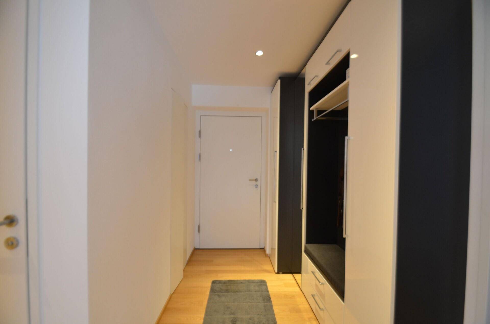 Moderner Eingangsbereich mit Holzboden und integrierter Garderobe mit Sitzgelegenheit.