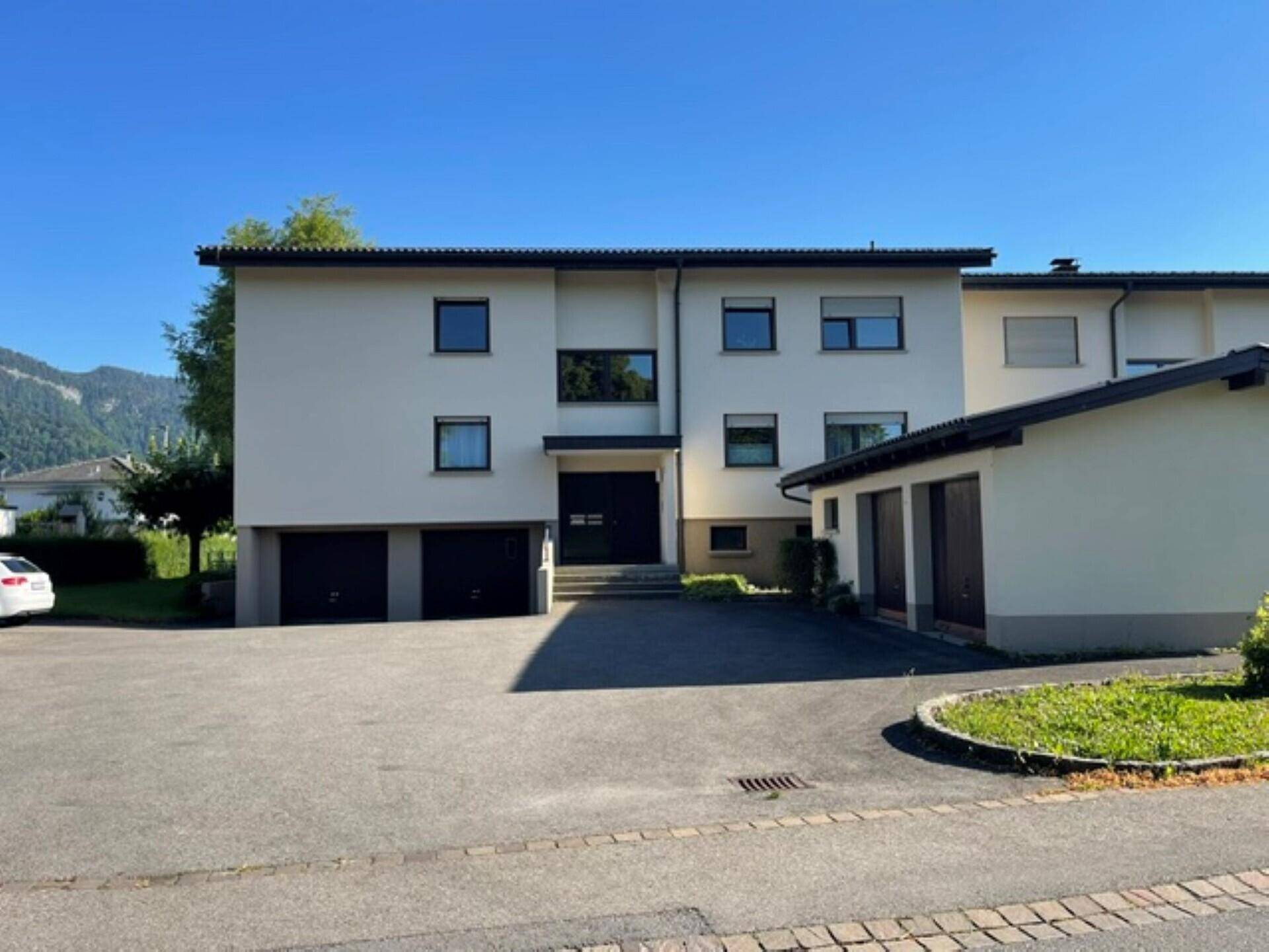 Vorderansicht des Gebäudes mit Zufahrt, Parkplätzen und Garagen.