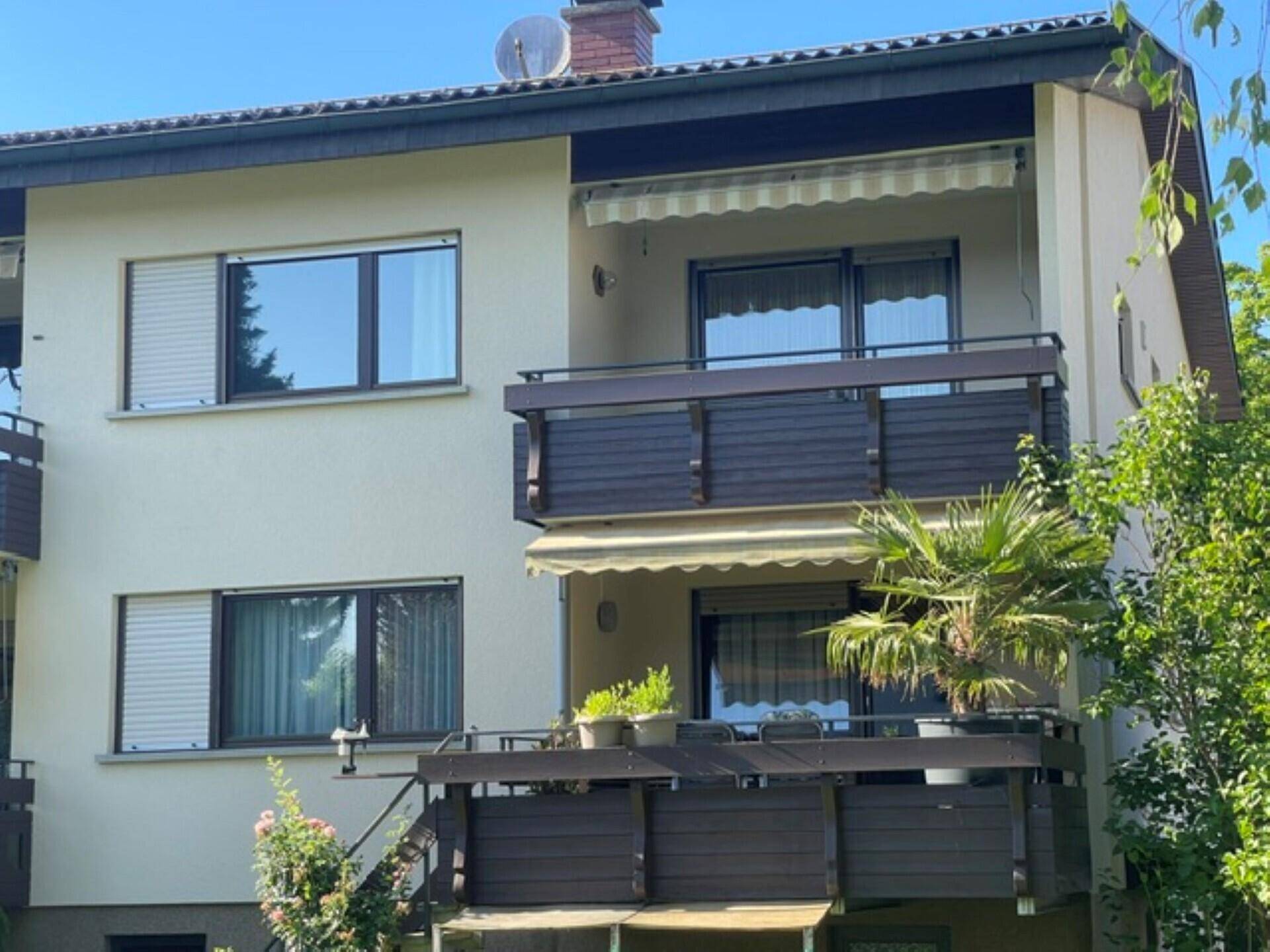 Fassade eines Mehrfamilienhauses mit mehreren Balkonen und Rollläden an den Fenstern.