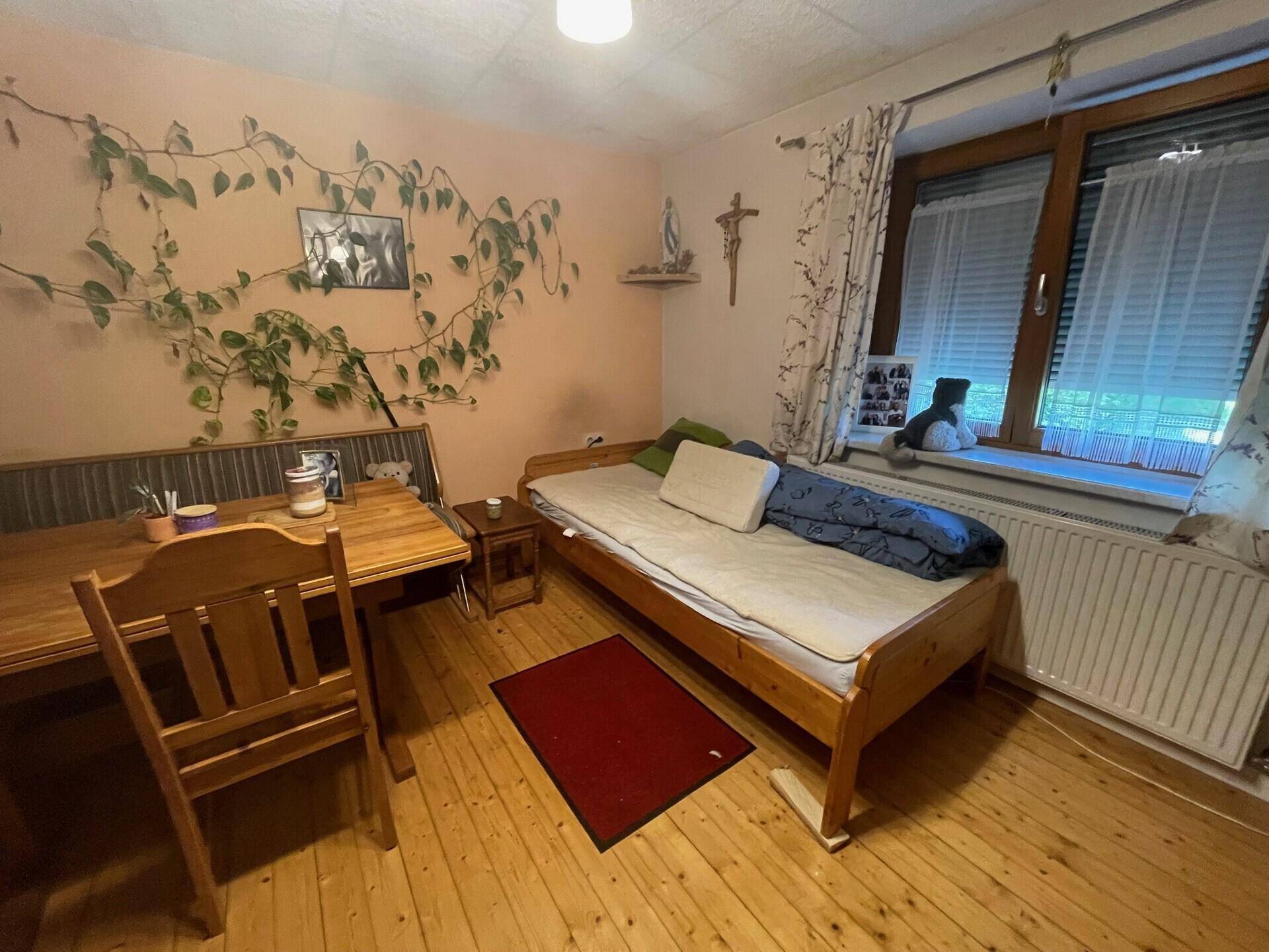 Gemütliches Schlafzimmer mit Holzdielenboden, Einzelbett und Holztisch.