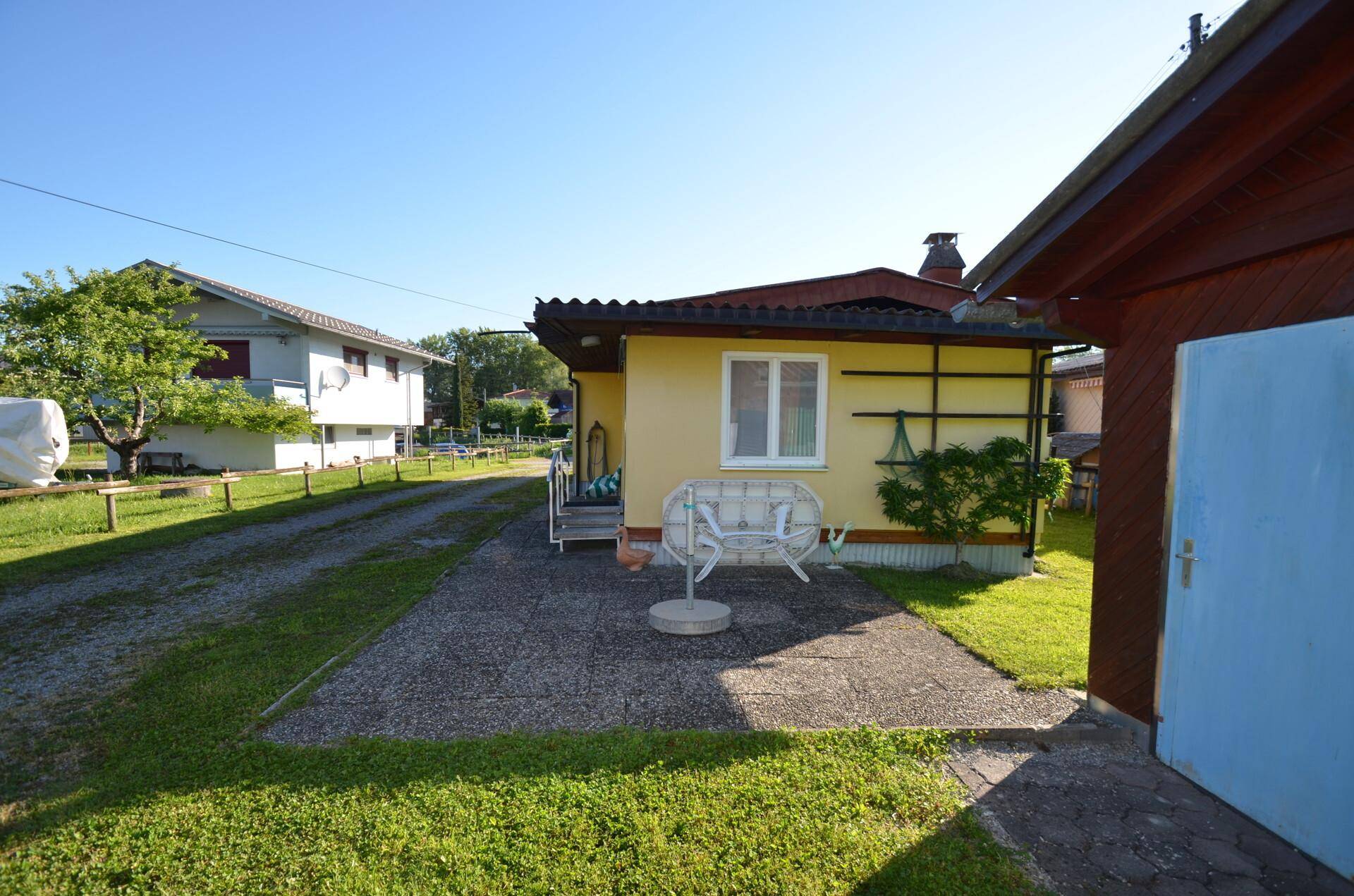 Rückseite des Hauses mit gepflastertem Bereich und Rasenfläche an einem sonnigen Tag.