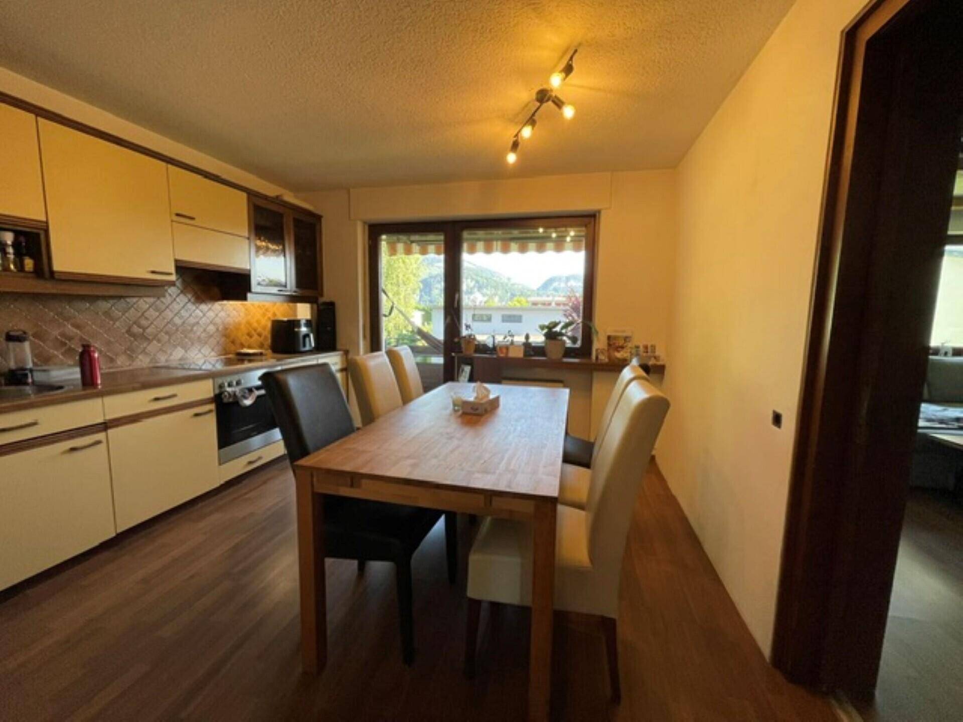 Helle Wohnküche mit Esstisch und Fensterblick auf die umliegende Berglandschaft.
