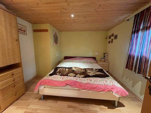 Gemütliches Schlafzimmer mit Holzwänden, Holzdecke und Laminatboden.