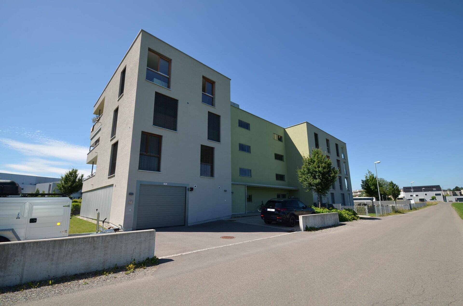 Ansicht des modernen Wohngebäudes mit integrierter Garage und Zufahrt auf der Vorderseite.