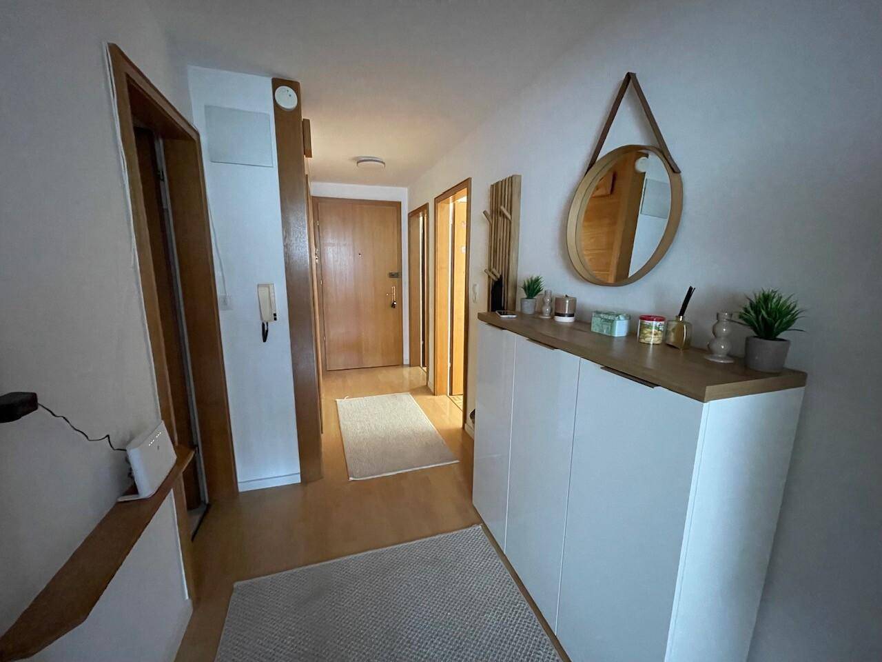 Heller Flur mit Holztüren, praktischem Schuhschrank und Spiegel, der einen einladenden Eingangsbereich schafft.