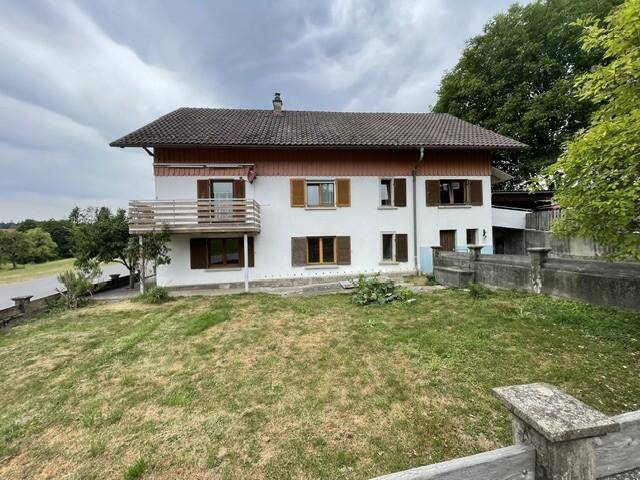 Rückansicht des Hauses mit Balkon und Blick auf die umliegende grüne Landschaft und Felder.