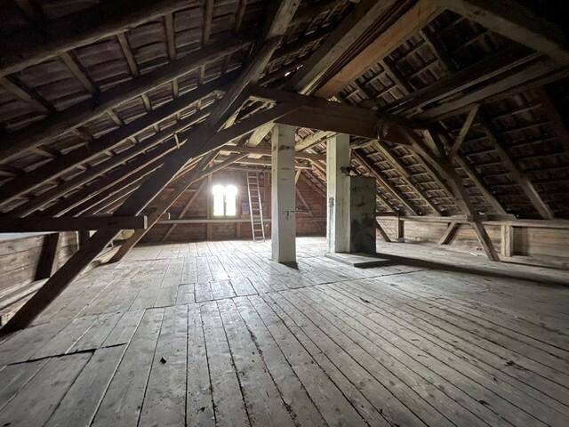 Geräumiger Dachboden mit sichtbaren Holzbalken und Holzdielenboden, bereit für einen Ausbau.