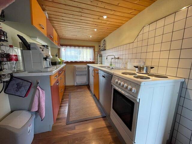 Schmale Küche mit Holzdecke, orangefarbenen Schränken und einfachen Geräten.
