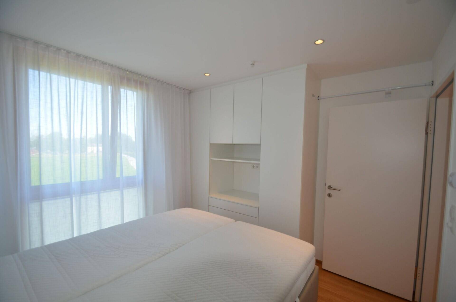 Schlafzimmer mit Doppelbett, Holzboden und praktischen weißen Einbauschränken.
