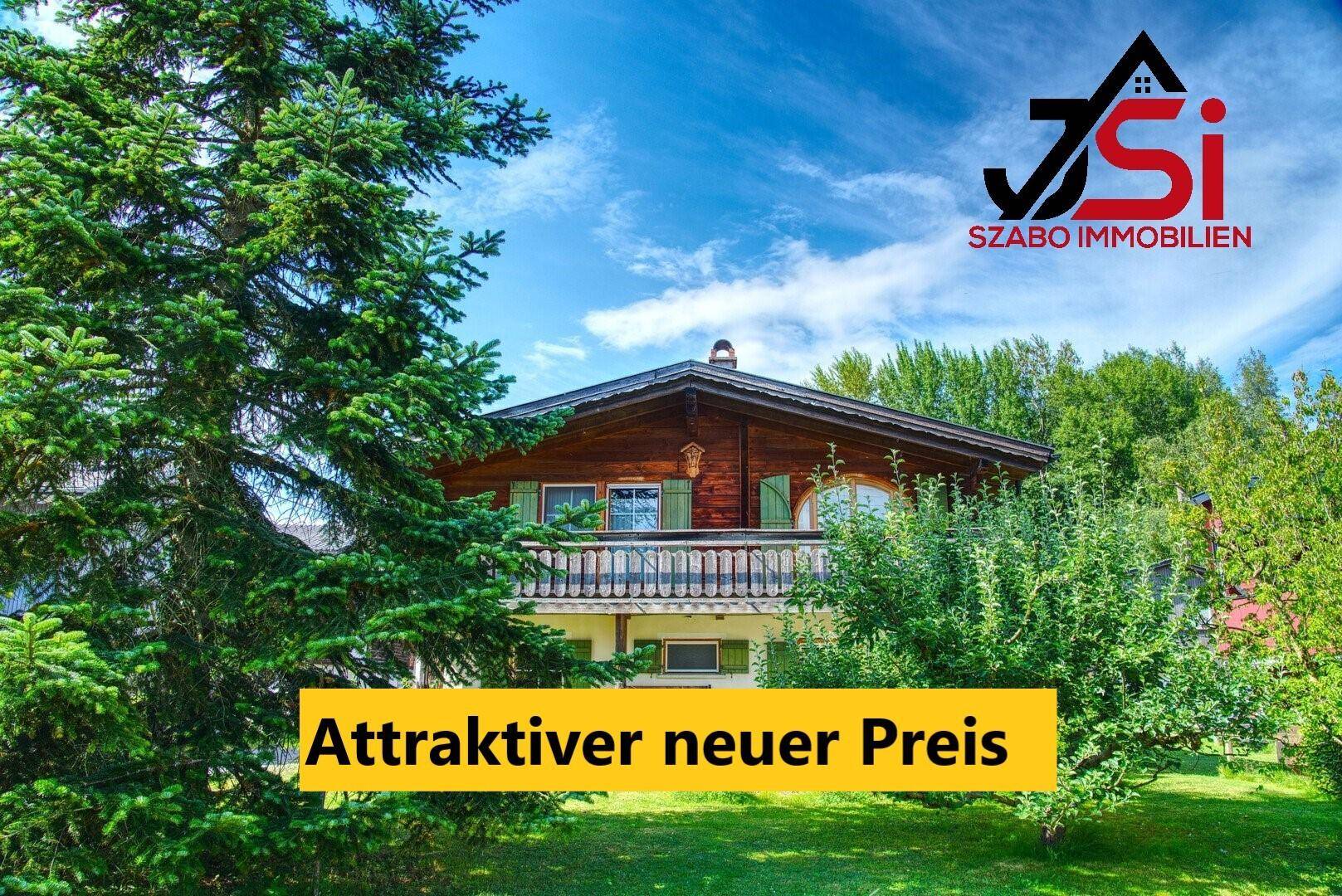 Charmantes Holzhaus mit Balkon, umgeben von einem weitläufigen grünen Garten und hohen Bäumen.