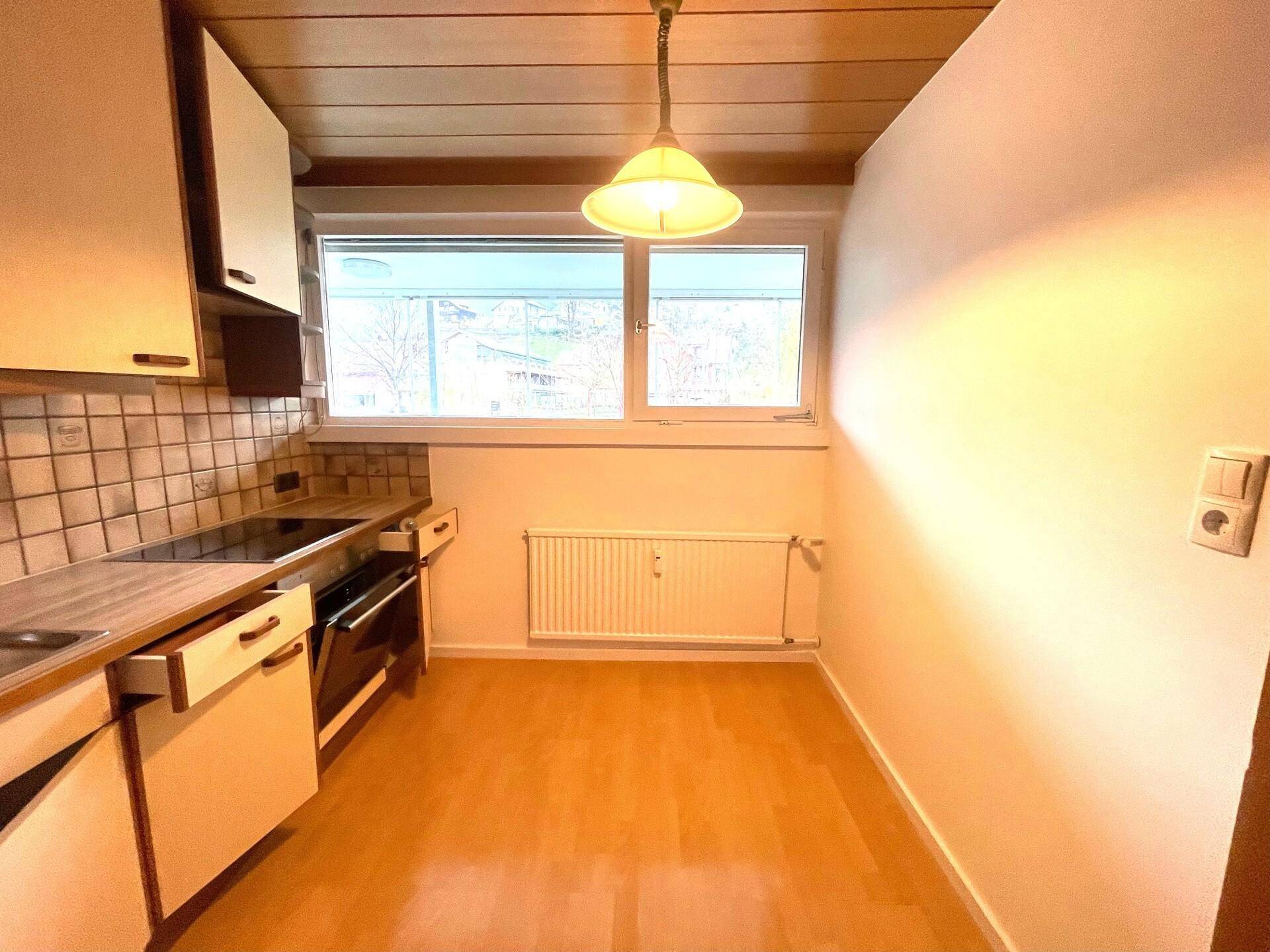 Funktionale Küche mit Holzdecke, Einbauschränken und Fenster mit Blick ins Grüne.