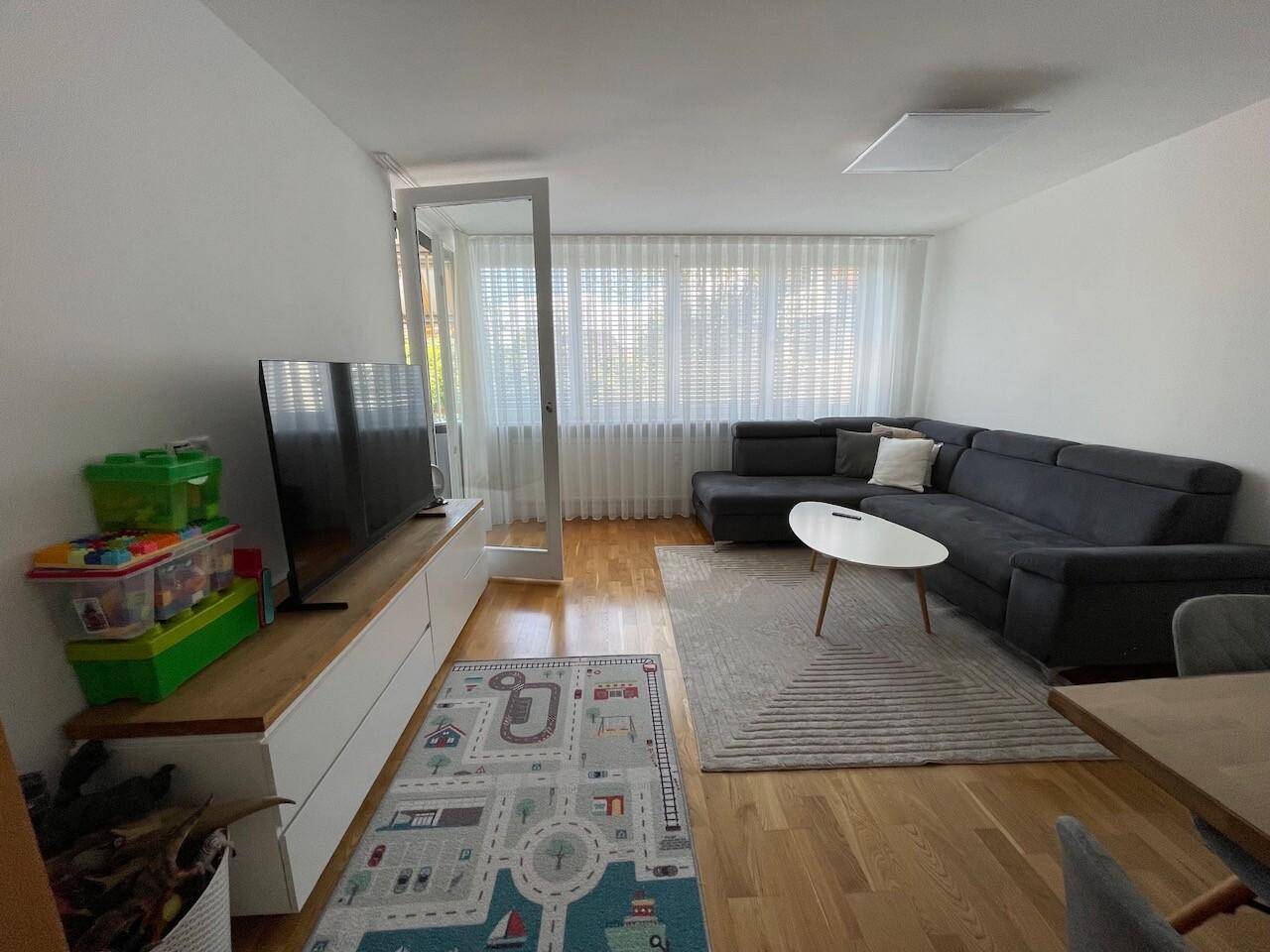 Freundliches Wohnzimmer mit bequemer Sitzecke, TV-Möbel und einem Essbereich, der zum Verweilen einlädt.