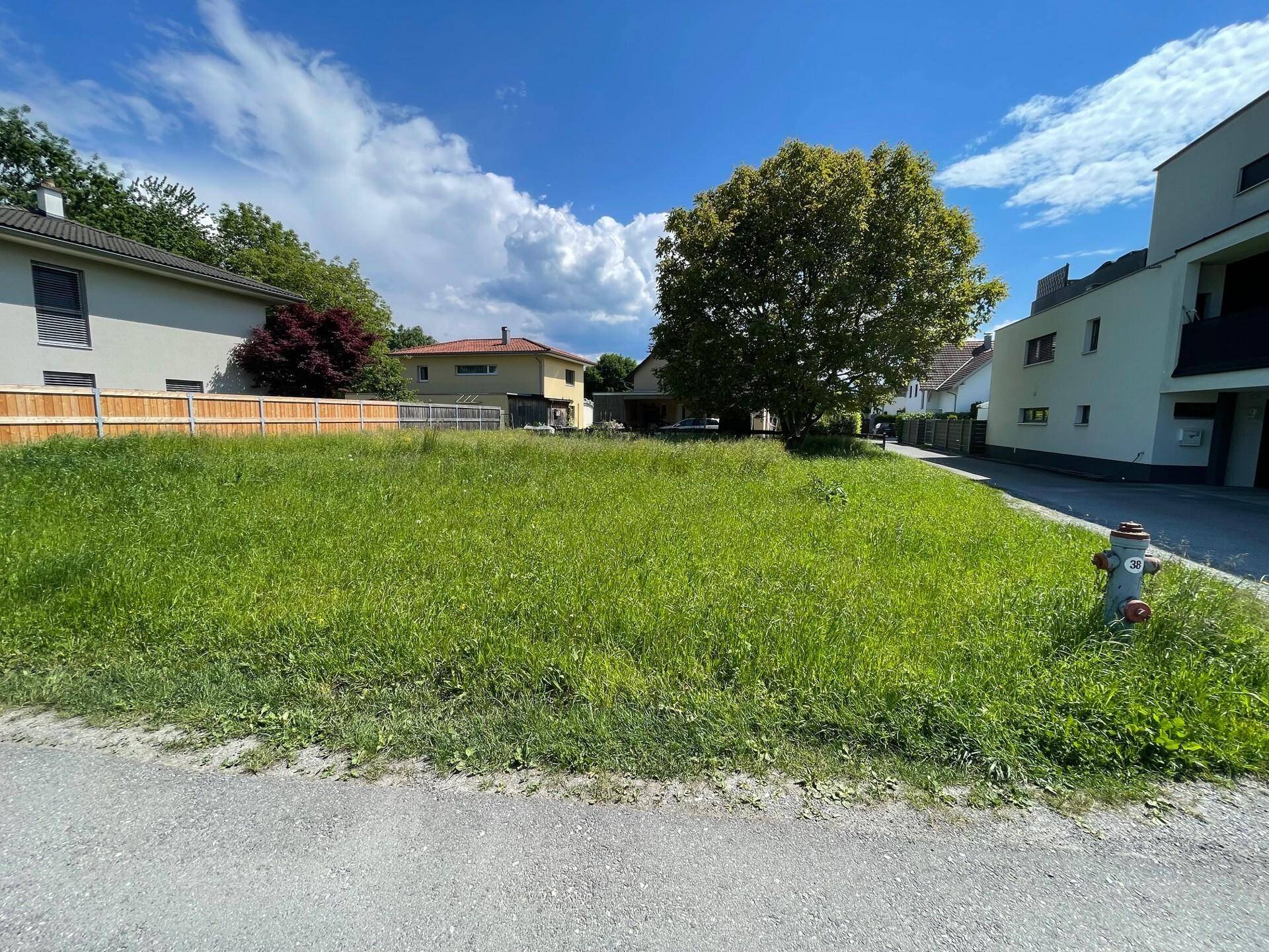 Offenes Grundstück mit Hydrant und Blick auf die umliegenden Wohnhäuser.