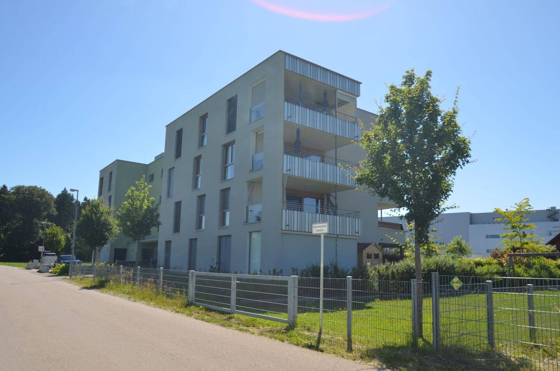 Modernes Mehrfamilienhaus mit Balkonen und zeitgenössischer Architektur in grüner Umgebung.