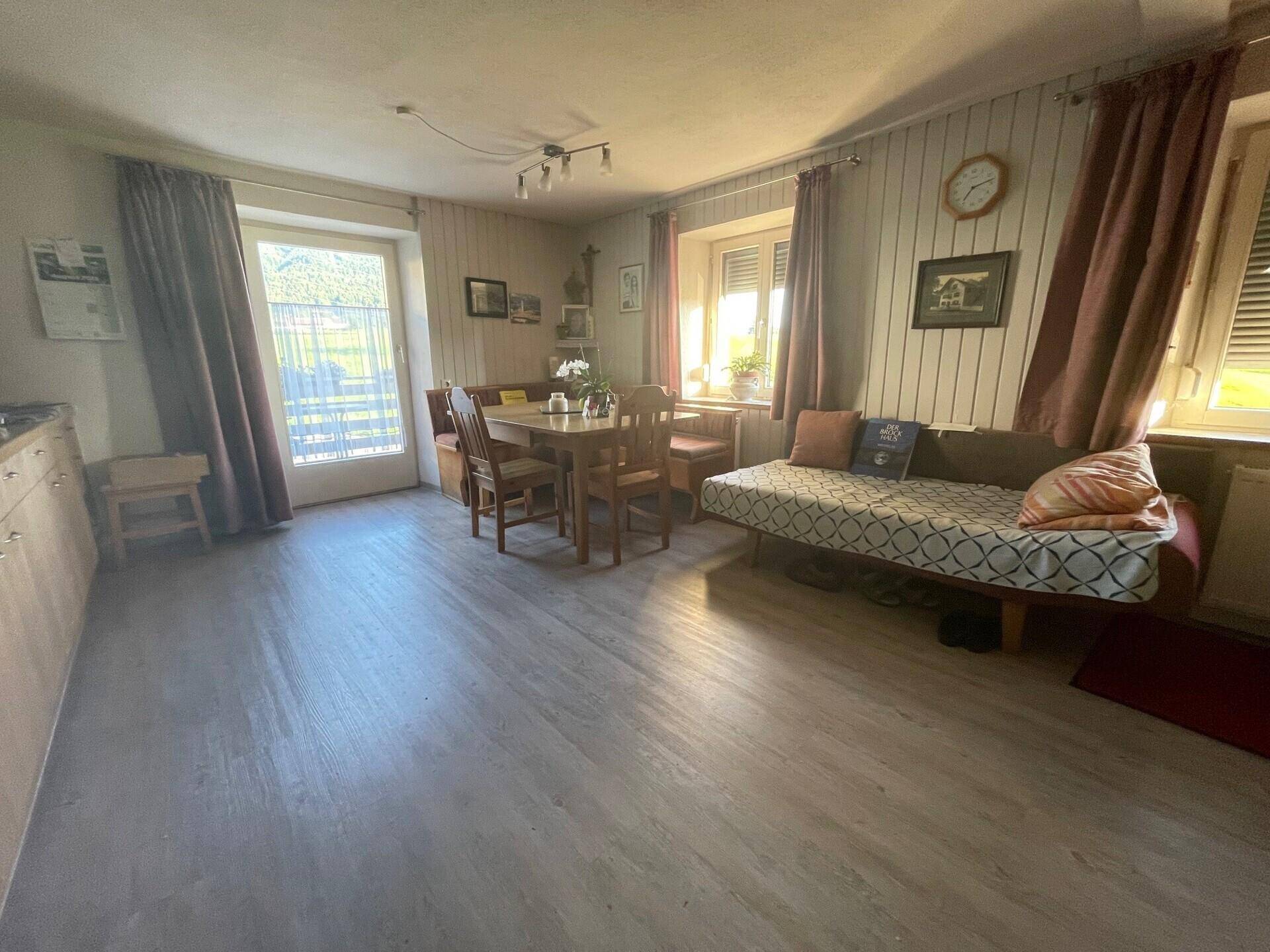Heller Wohn-Essbereich mit Laminatboden, Esstisch und Sofa, mit Zugang zum Außenbereich.