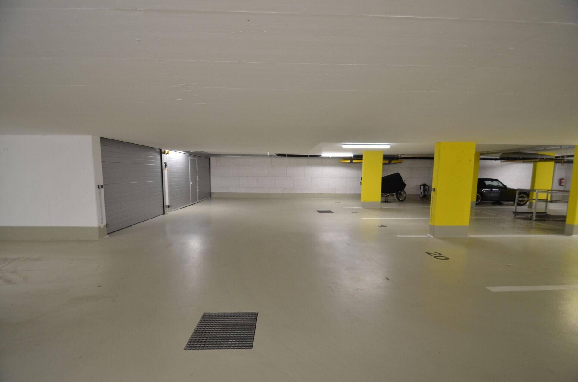 Geräumige Tiefgarage mit gelben Säulen und markierten Stellplätzen für mehrere Fahrzeuge.