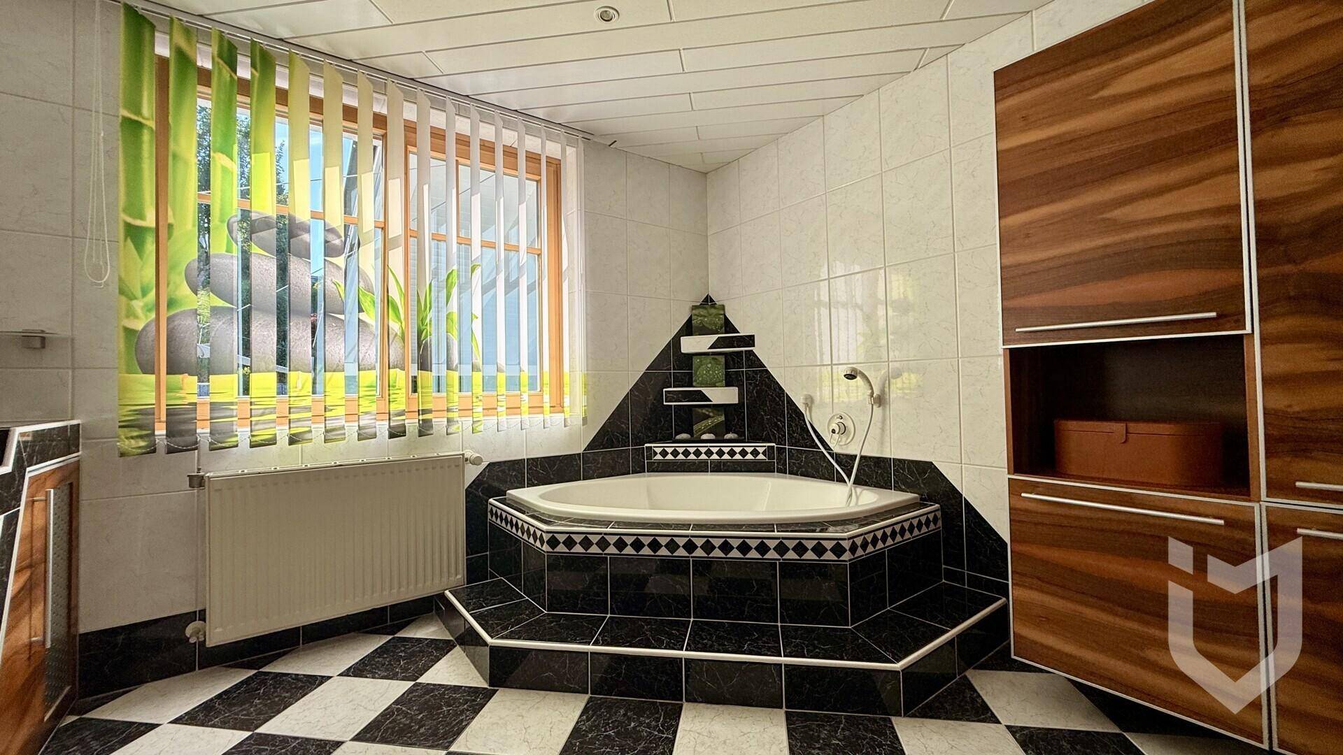 Badezimmer mit Eckbadewanne, markanten schwarz-weißen Fliesen und Holzschränken.