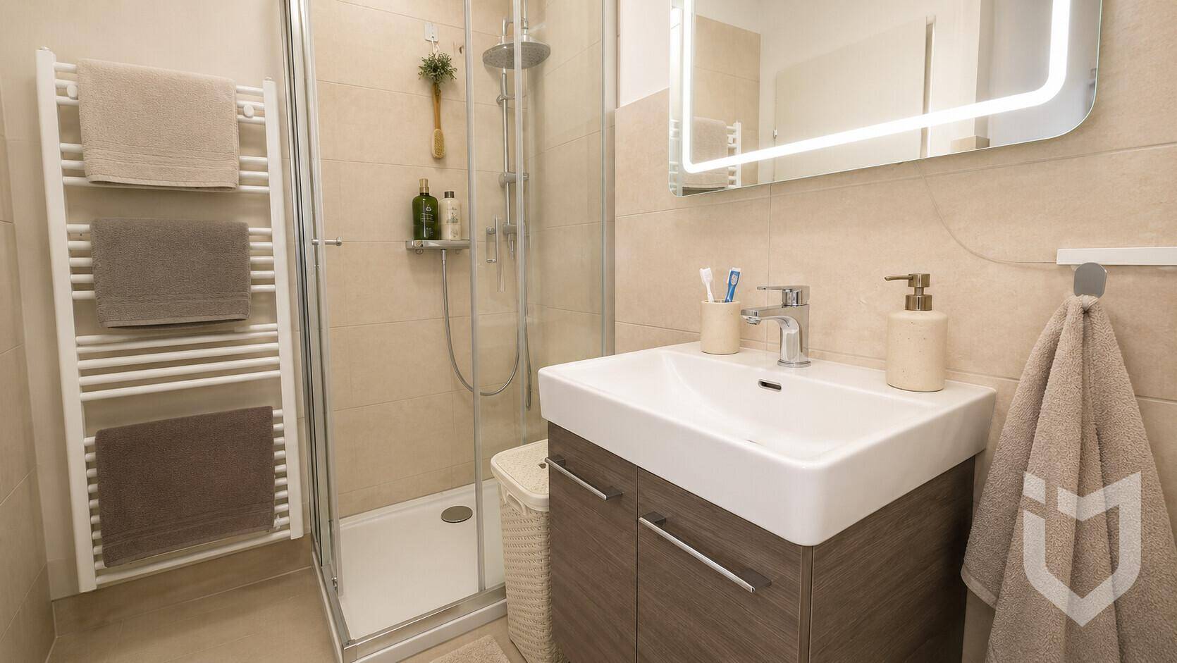 Helles Badezimmer mit Duschkabine, modernem Waschbecken und beheiztem Handtuchhalter.