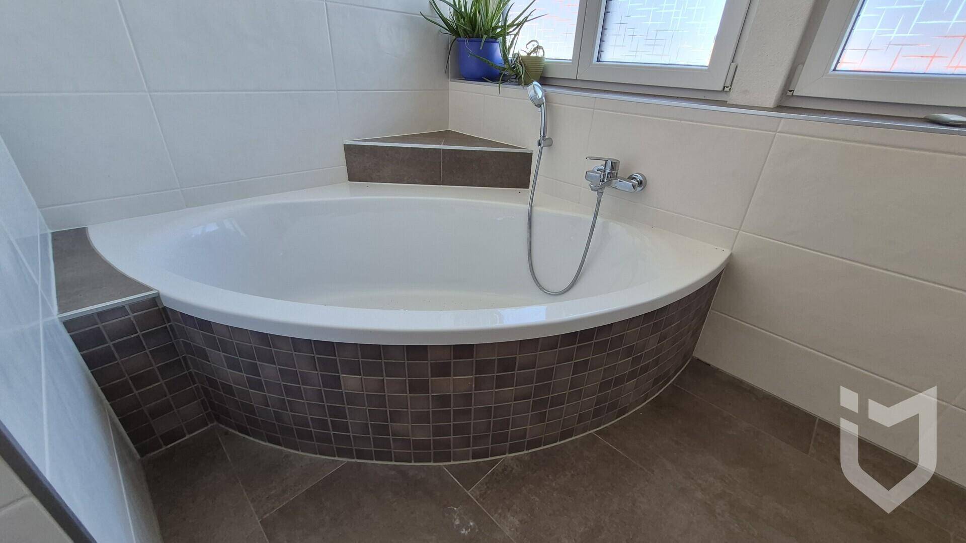 Modernes Badezimmer mit Eckbadewanne und Fliesen in neutralen Farbtönen, gut beleuchtet.