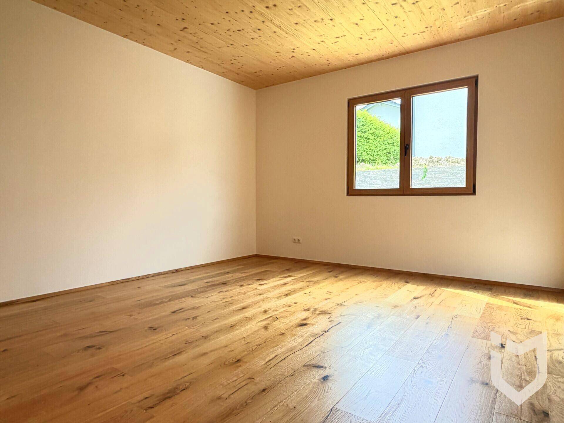 Ruhiges Schlafzimmer mit Holzboden und Holzdecke, einem Fenster mit Blick ins Grüne, ideal zum Entspannen.