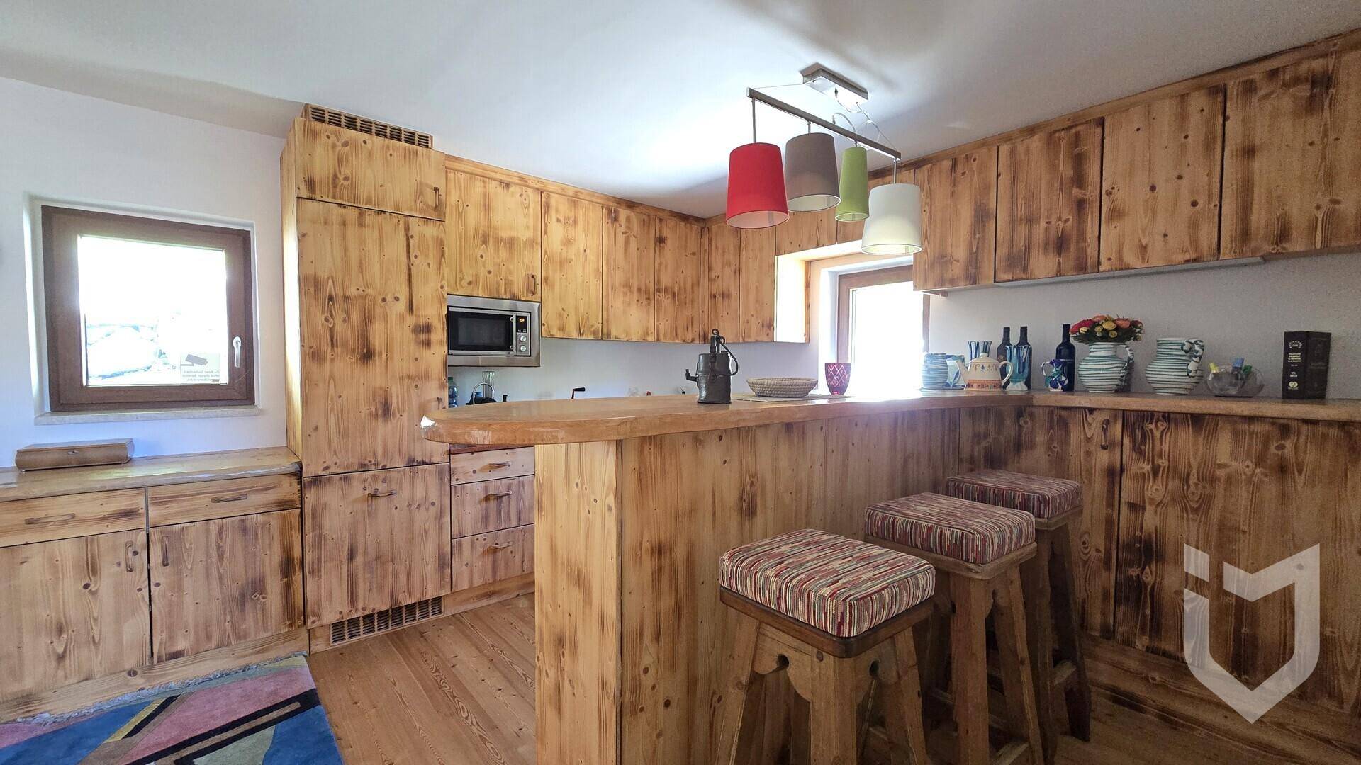 Rustikale Küche mit massiven Holzschränken, integrierter Mikrowelle und einer gemütlichen Frühstücksbar.