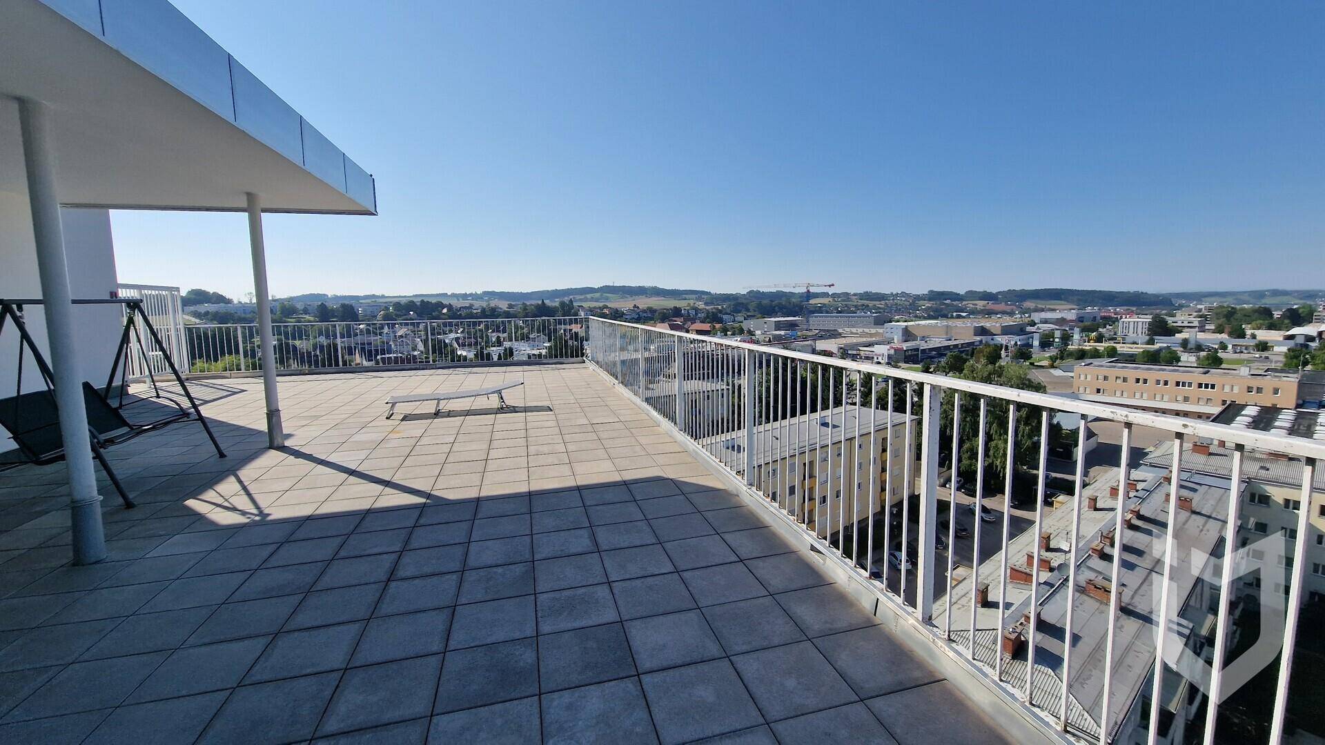 Große Dachterrasse mit Fliesenboden und weitem Panoramablick über die Stadt und Hügel.